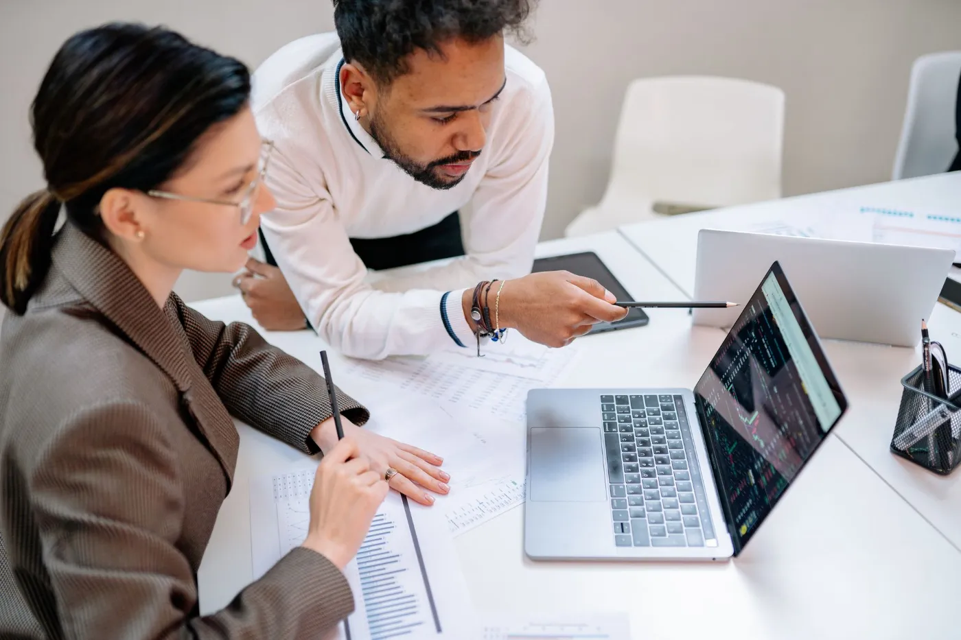 Two colleagues review work together on a laptop.