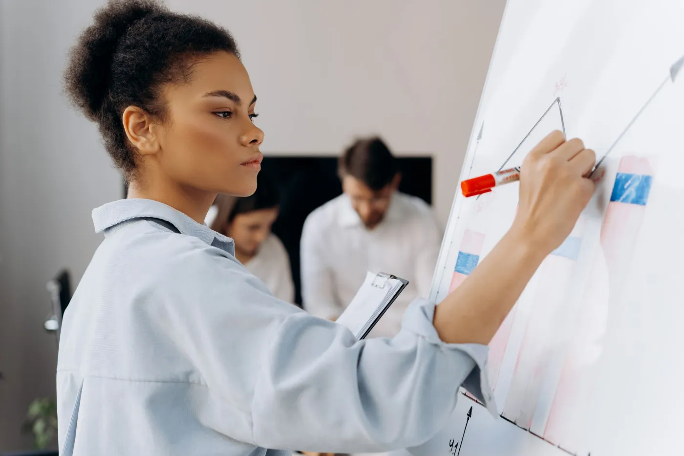 A practitioner draws a diagram on a whiteboard while colleagues follow along.
